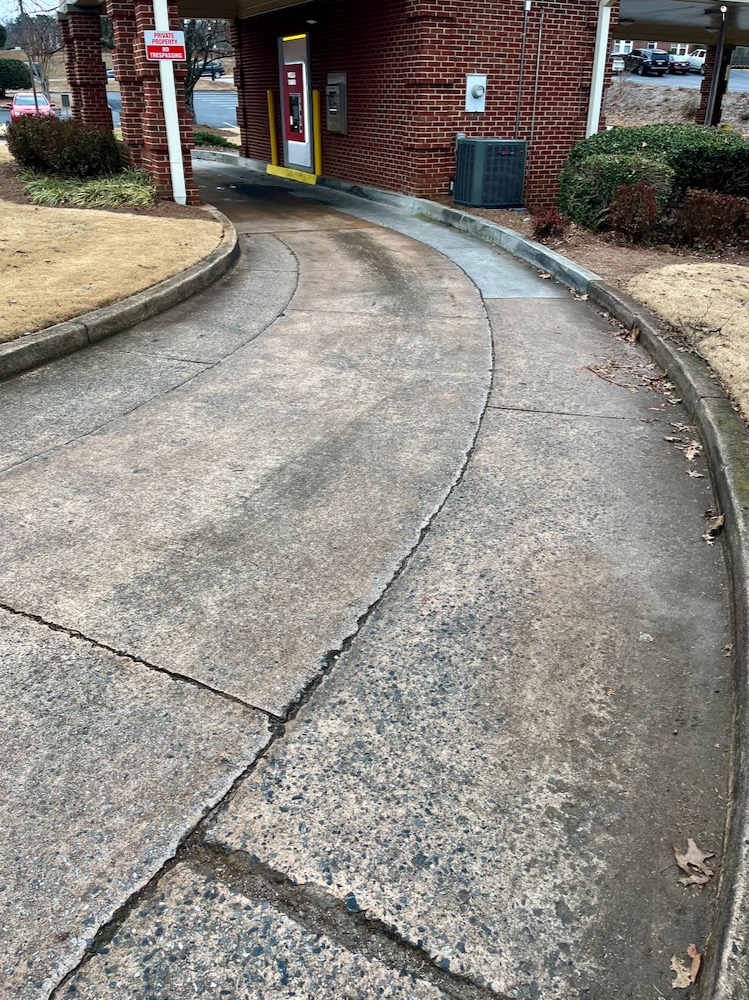 A concrete driveway covered in oil stains and tire marks - photo